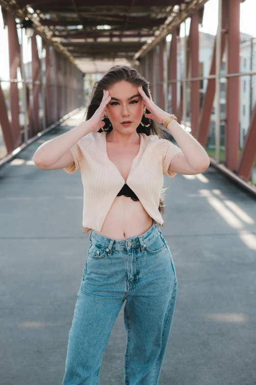 a woman is posing in jeans and a crop top