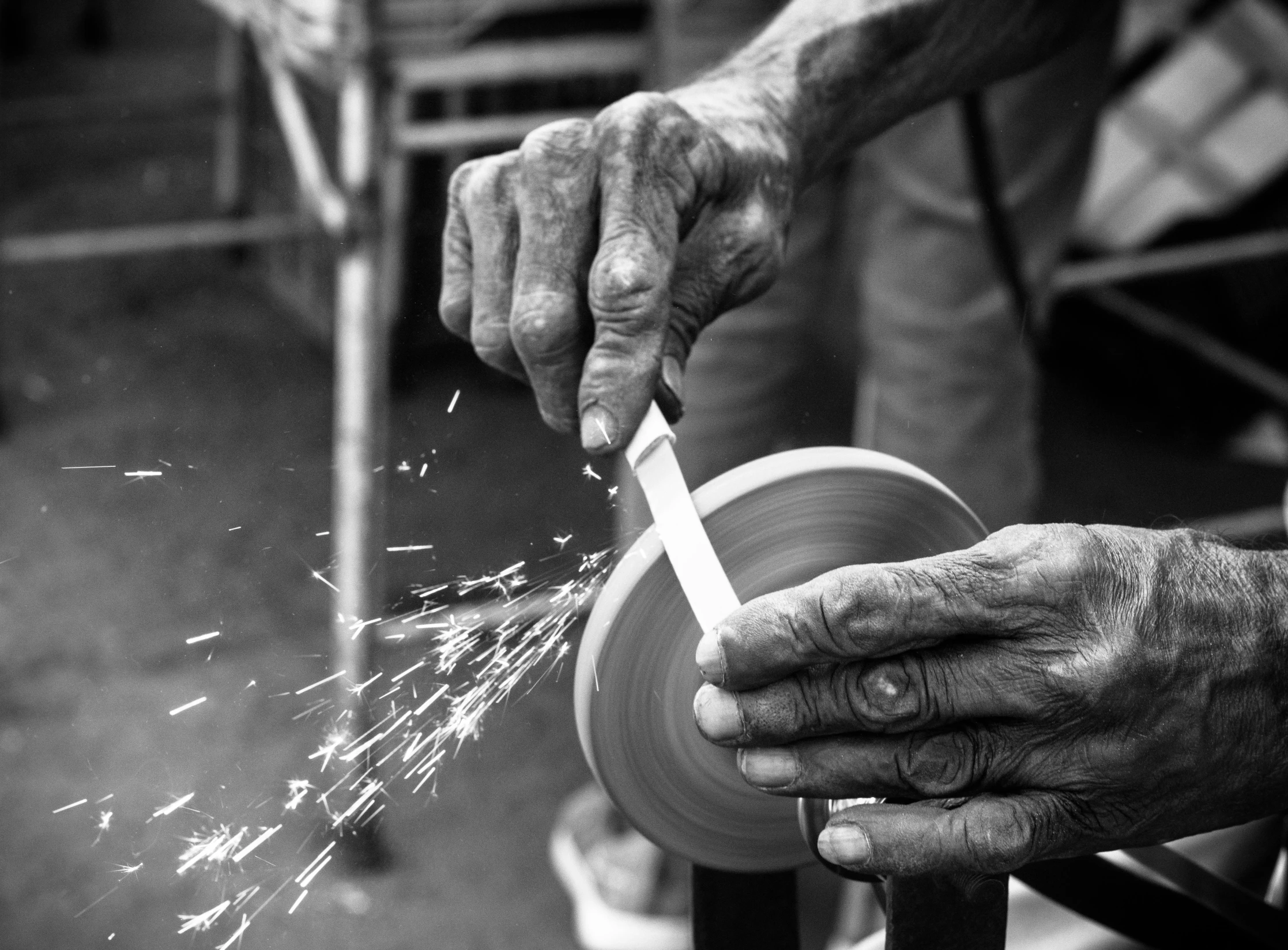 an old man holding a metal pipe and working with grinders