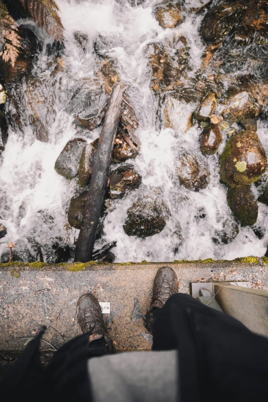 the feet are standing by the water near rocks