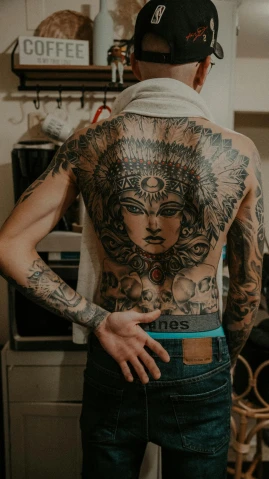 a man with a full back tattoo in a kitchen