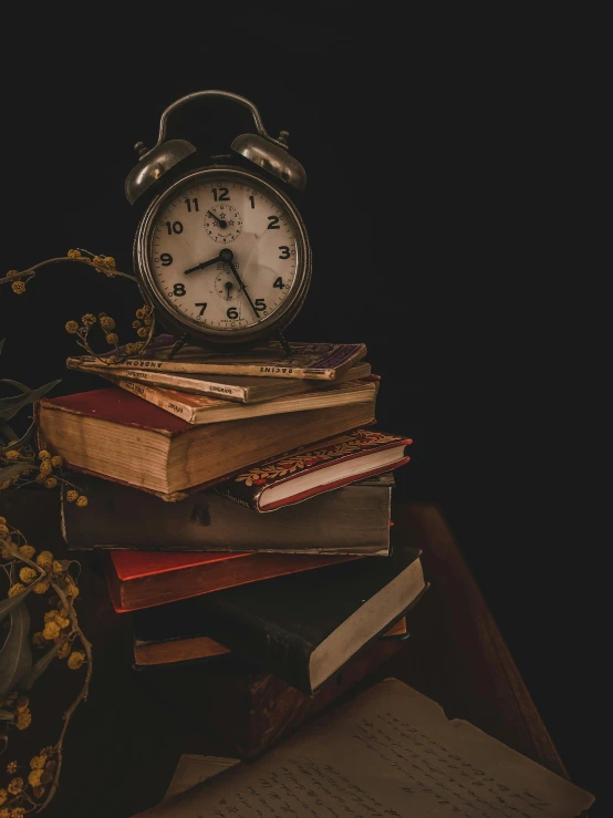 an alarm clock sitting on top of a pile of books