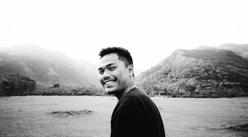 black and white pograph of man standing in field smiling