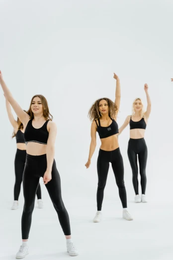 a group of girls in black yoga suits in dance poses