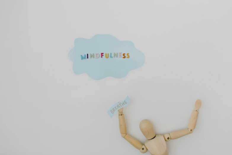 small wooden mannequin with a sign above it on a white wall