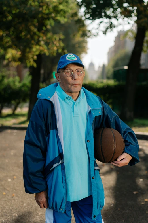 an old man is holding a basketball while walking