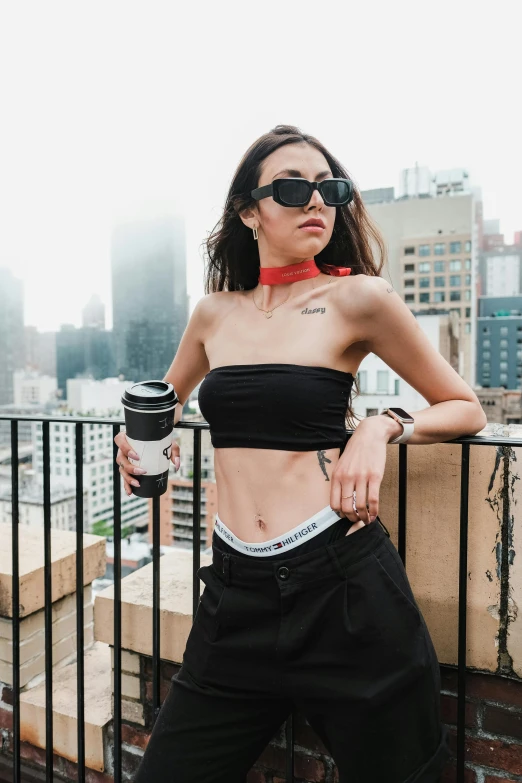 a woman posing with a coffee cup on her lap while wearing black pants