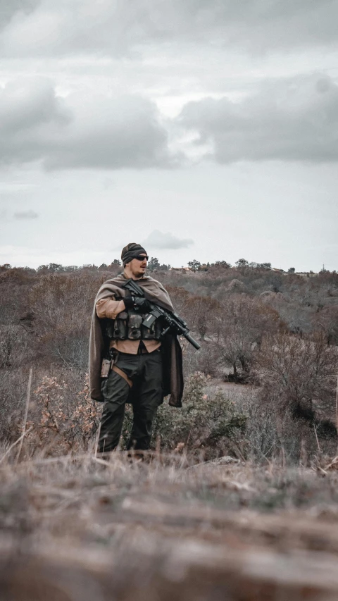 a man is holding a rifle in the wilderness