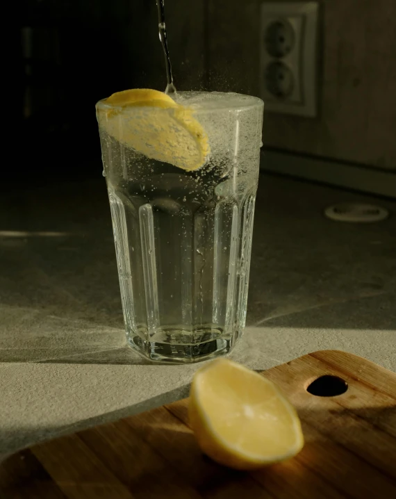 a piece of lemon being added to a glass of water