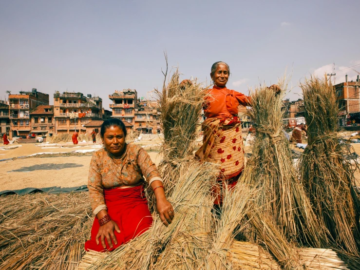 two women who are sitting in some hay