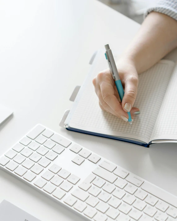 a woman is holding a pen and writing on a notebook