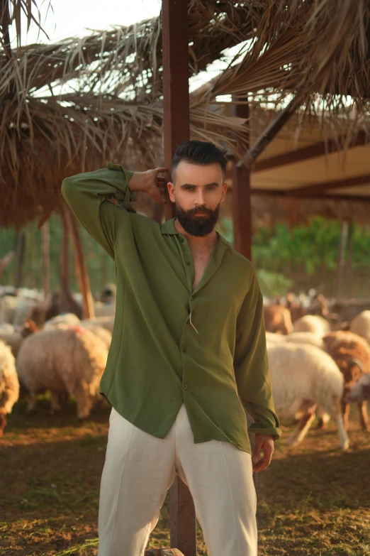 the bearded man in a green jacket stands under a hay roof