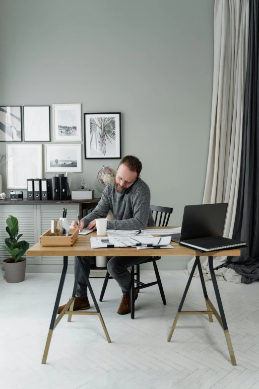 a man sitting at a desk with a laptop computer and books