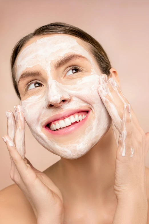 a girl is touching her face with mud on her cheek