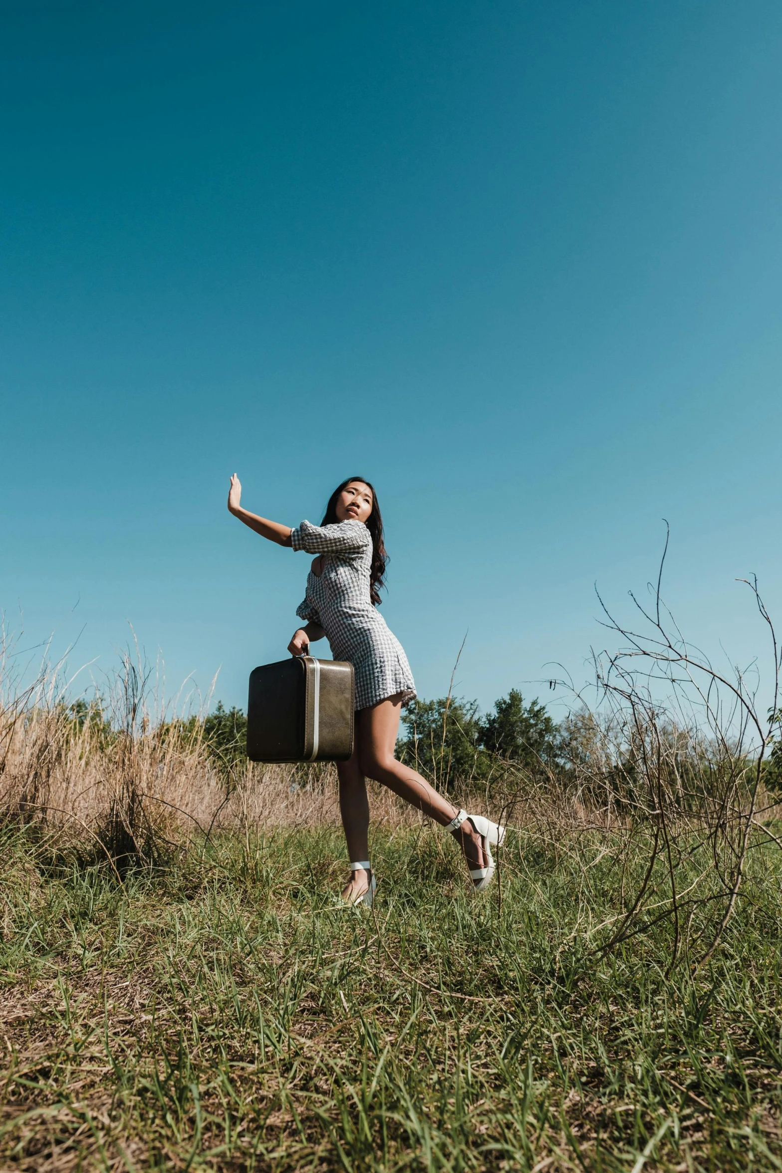 girl holding an open suitcase running through a field