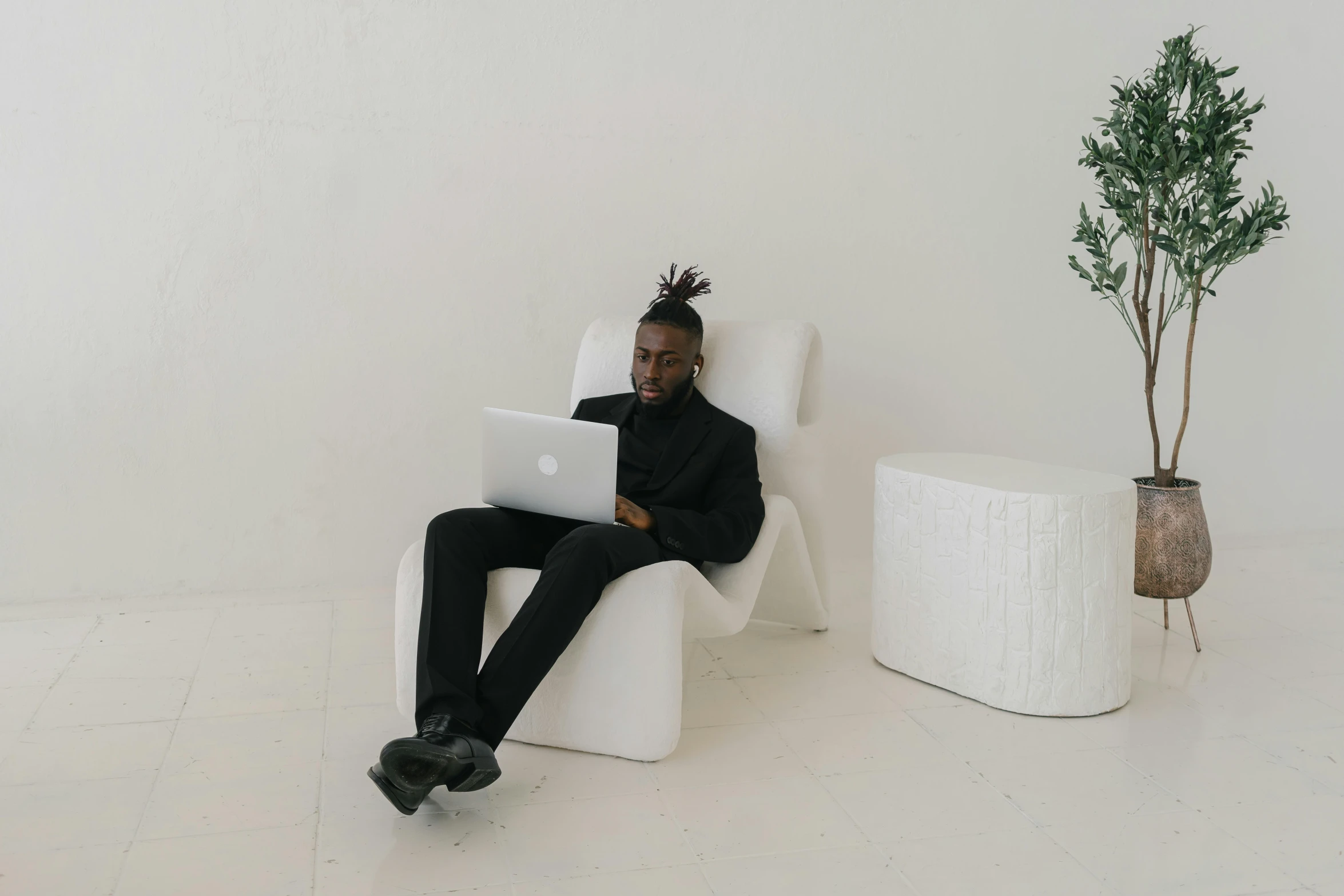 a man sitting on a chair working on his laptop