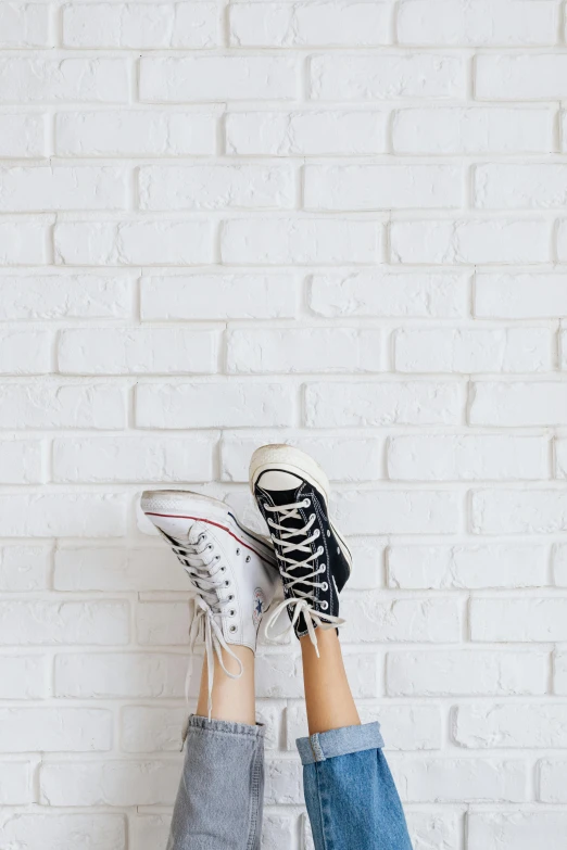 person standing against a wall, feet up on top of their shoes