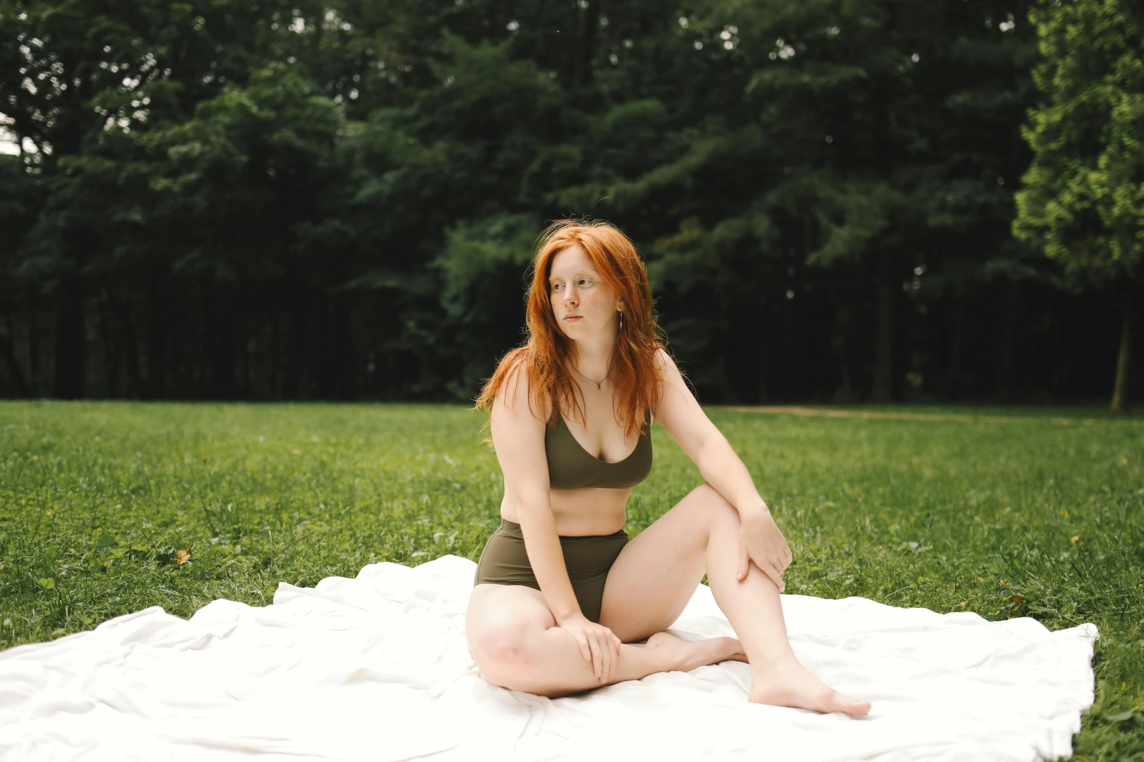 a beautiful young woman in a bathing suit sitting on a white towel