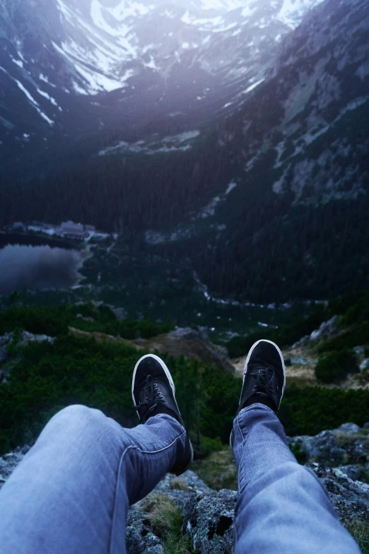 a man sitting down looking over a field and mountains