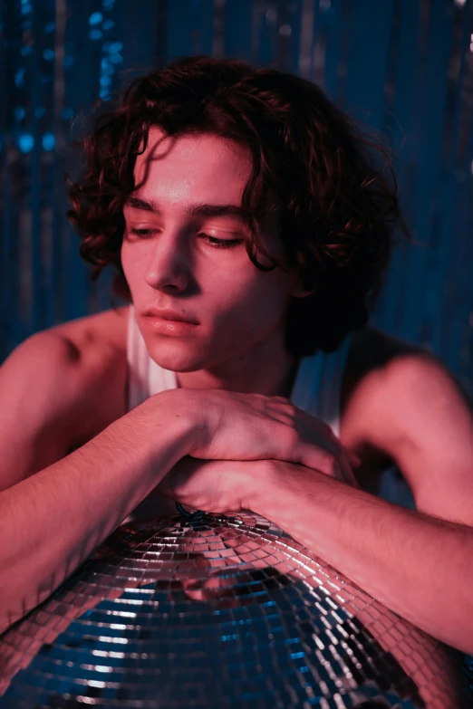 a man with curly hair and wearing silver sitting down