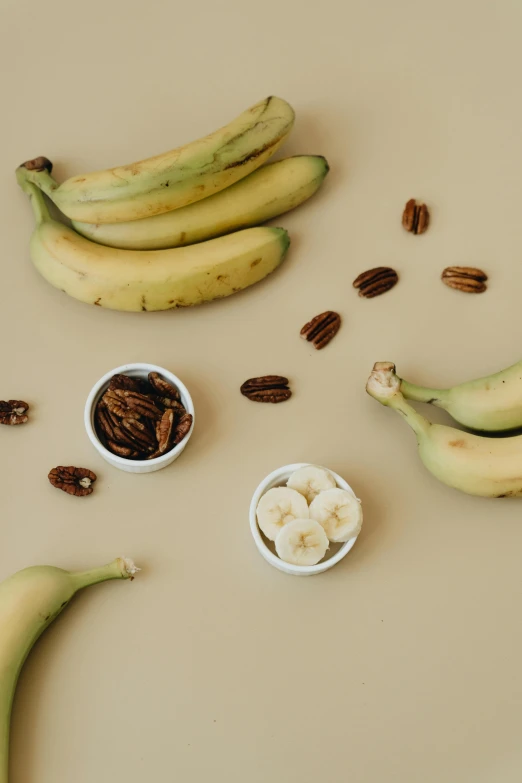 a bunch of bananas and a bowl with nuts around them