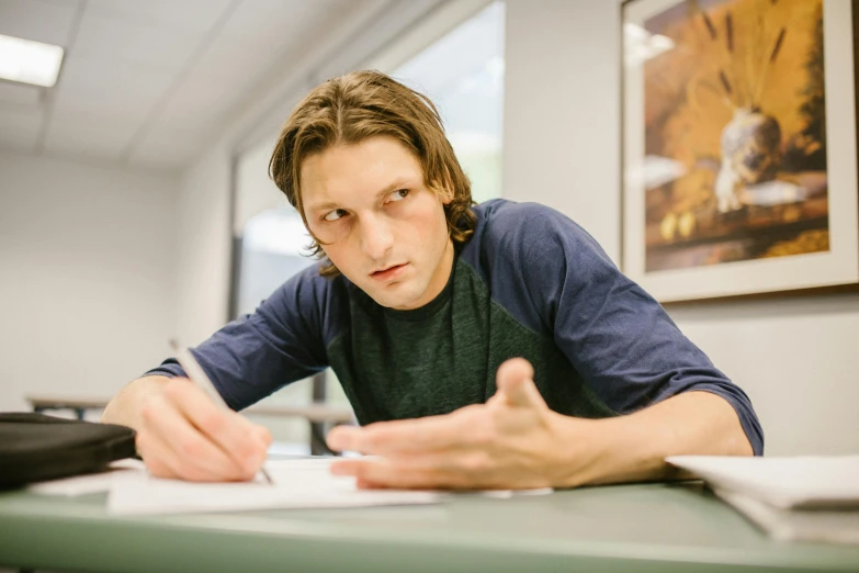 a man that is sitting at a table with a pen