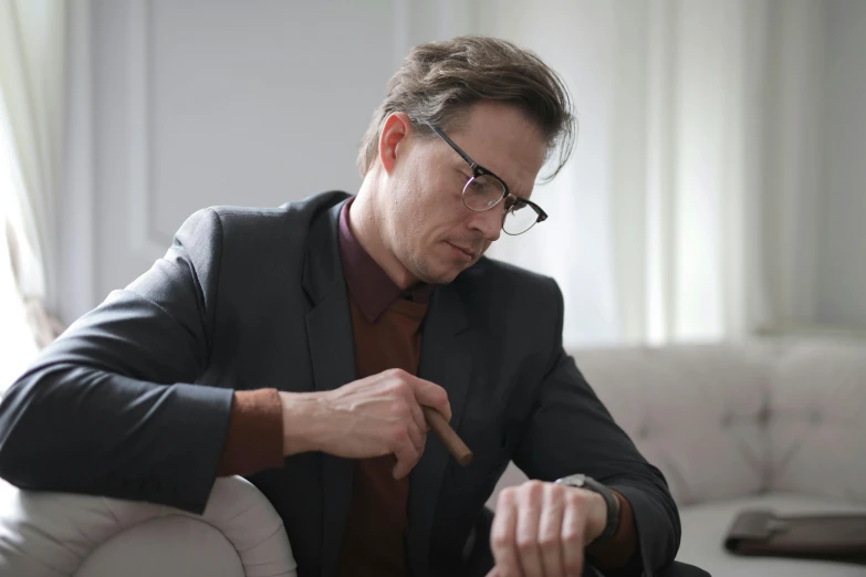 a man with glasses holding a pipe and looking at soing