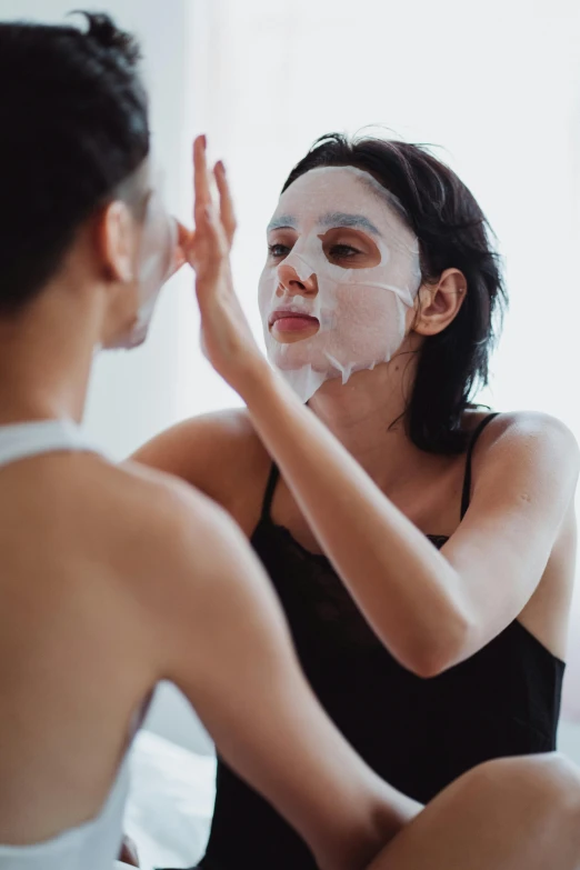 a woman wearing a white mask is talking to another woman