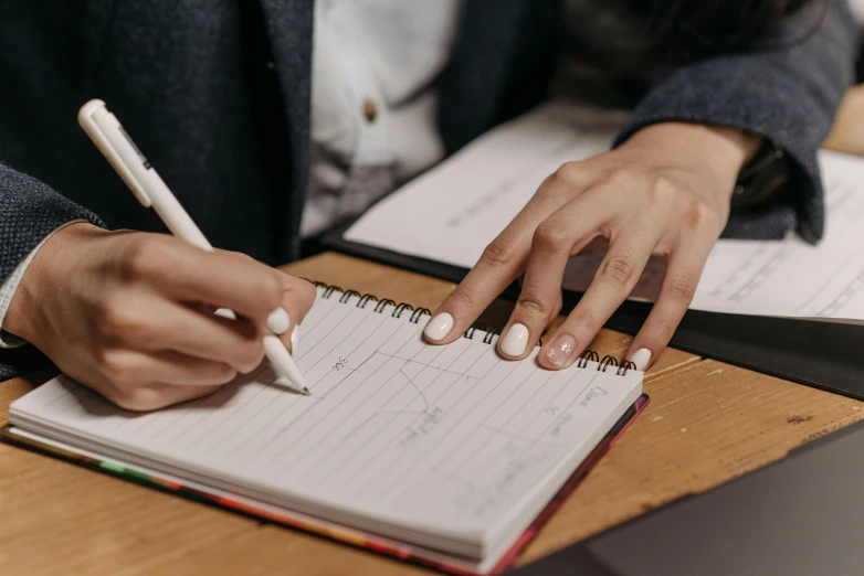 someone holding a pen writing in a notebook