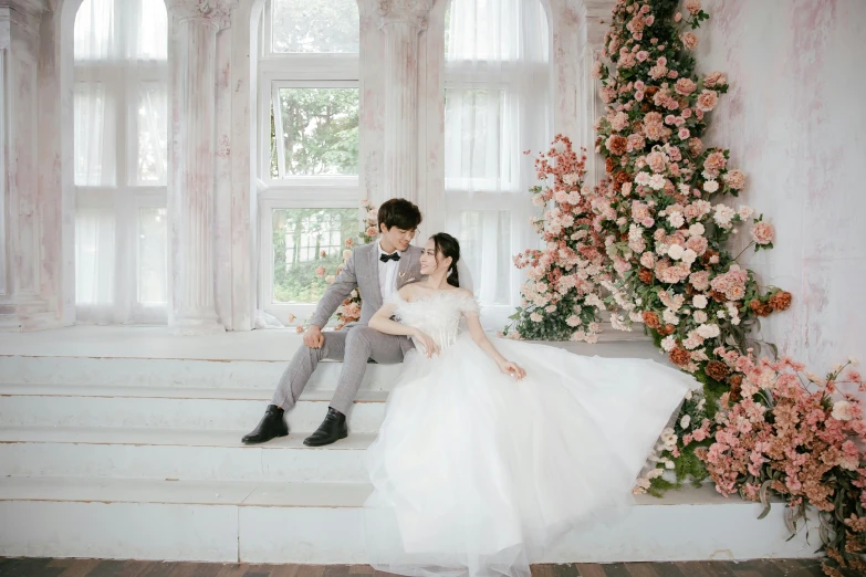 a young bride and groom sitting on a staircase next to a flower bush