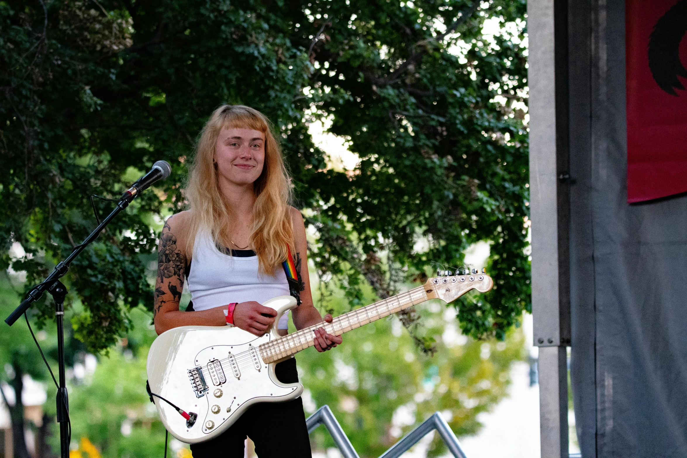 a woman playing a guitar near microphones