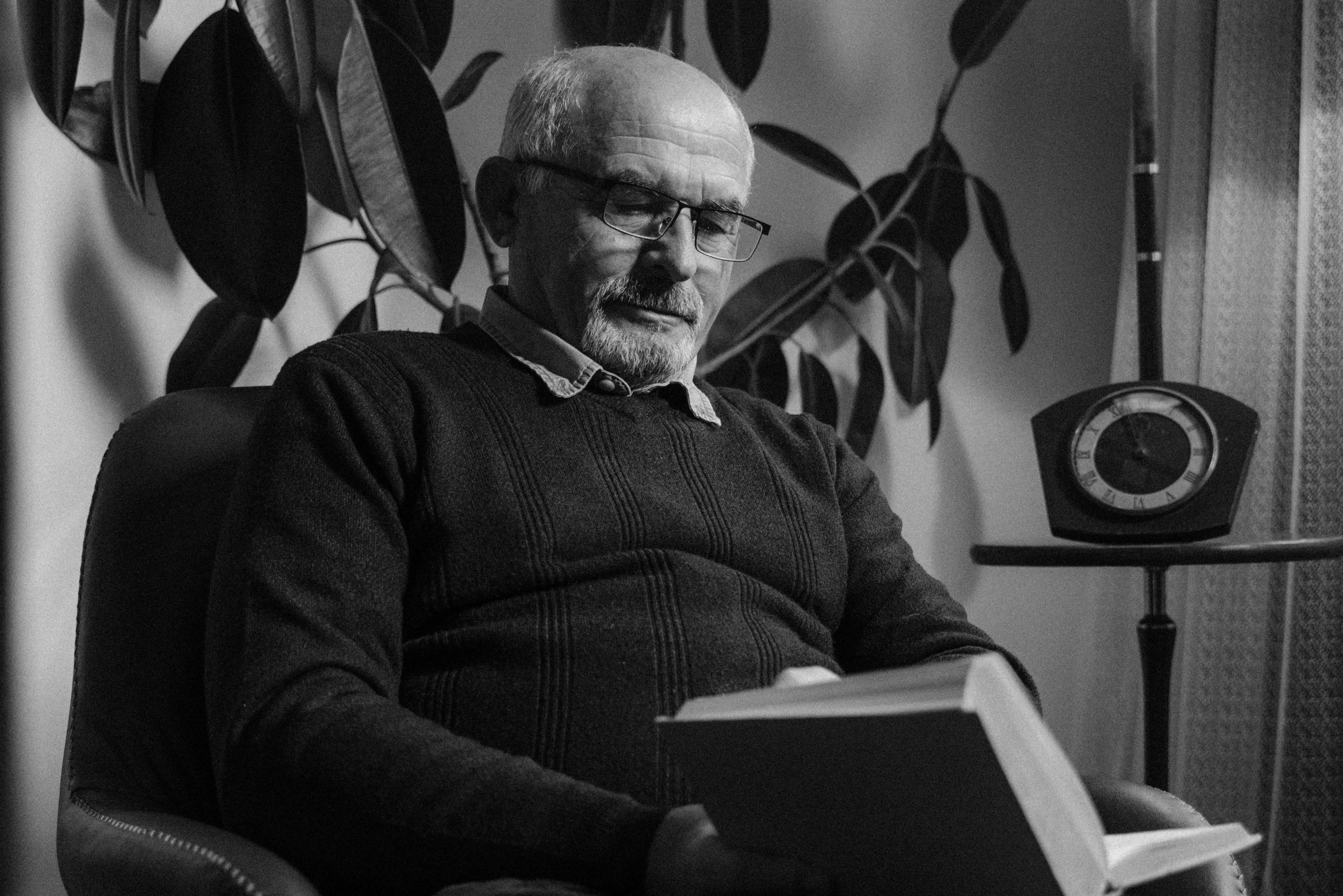 an older man sitting in a chair and reading