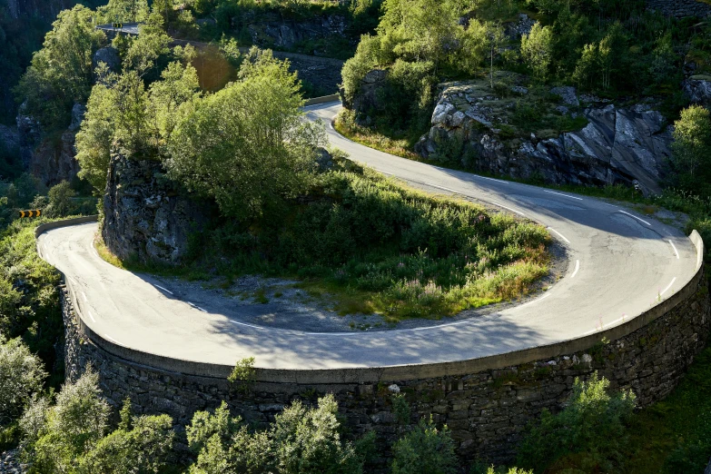 a motorcycle is on the curved road in the mountains