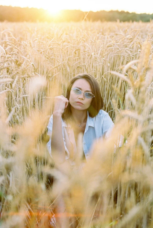 a young woman wearing glasses standing in a field