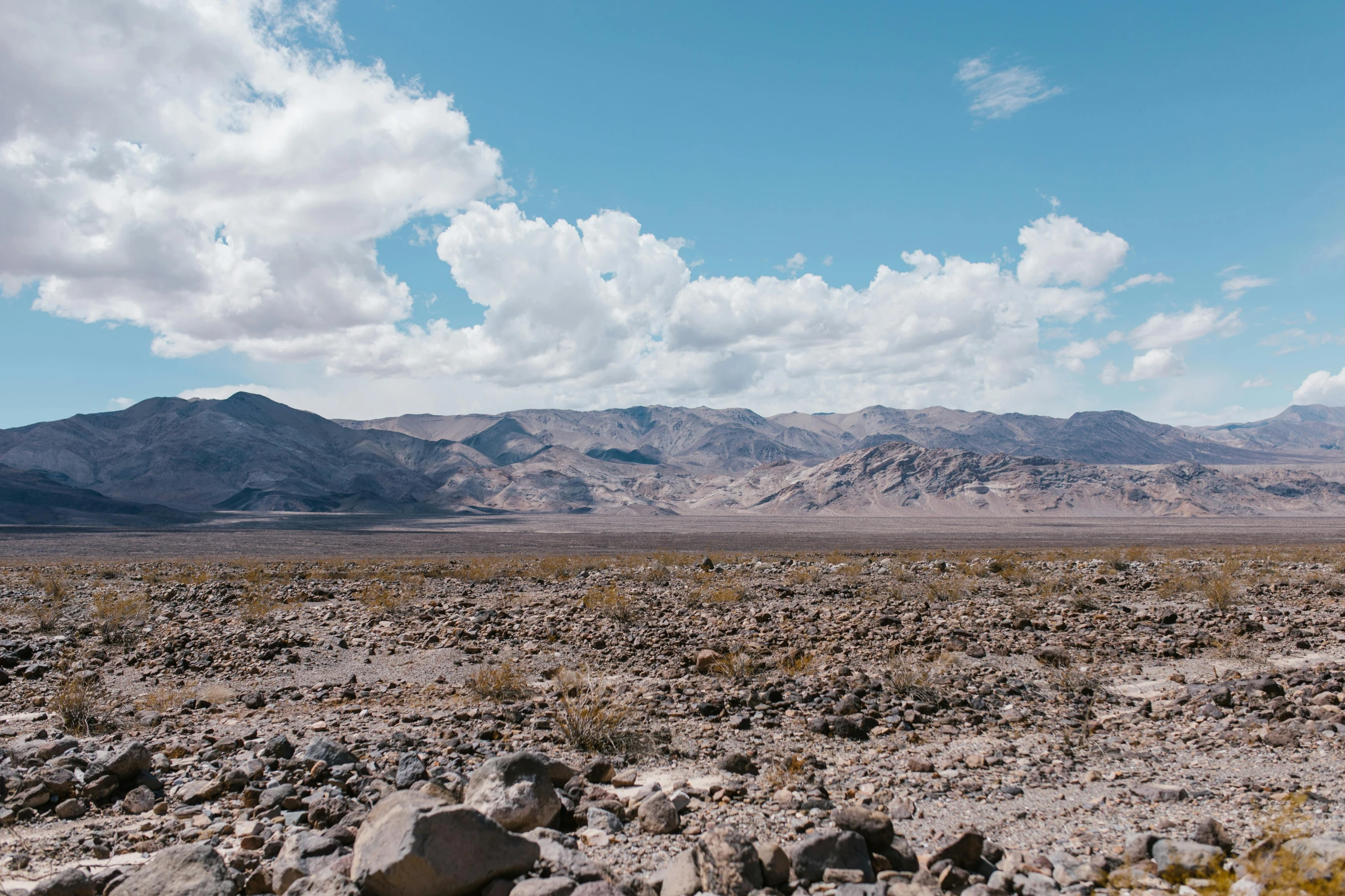 mountains are seen in the distance behind an arid area