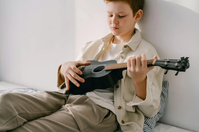 young child playing an instrument leaning against a wall