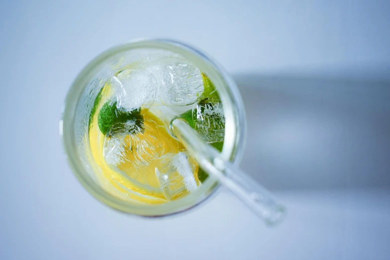 a glass with drink and two straws on a white table