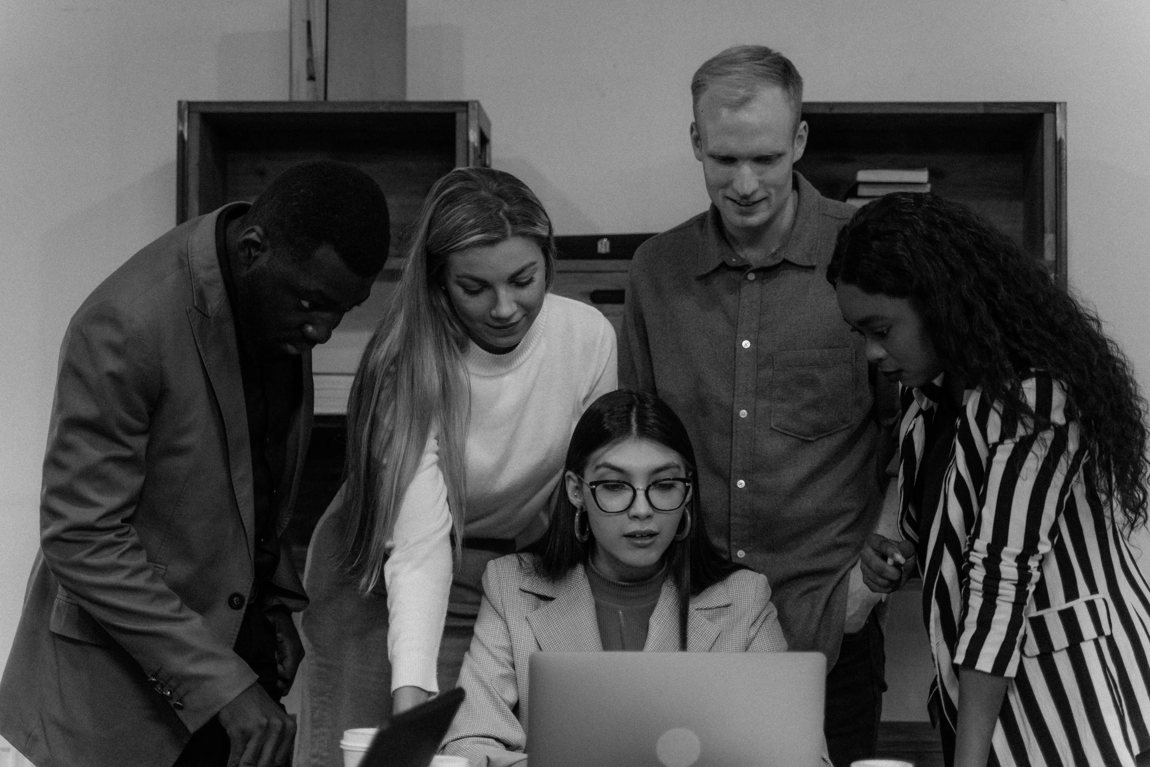 a group of people standing around a laptop