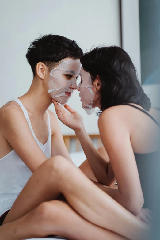 two women looking at their faces in paper under the covers