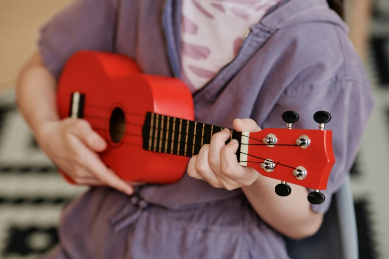 a close up of someone playing an orange ukelel