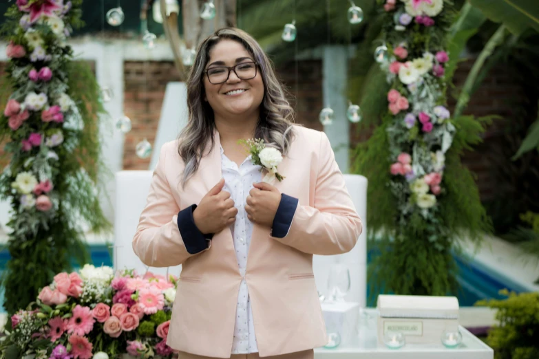 a smiling woman in pink is standing by flowers and candles