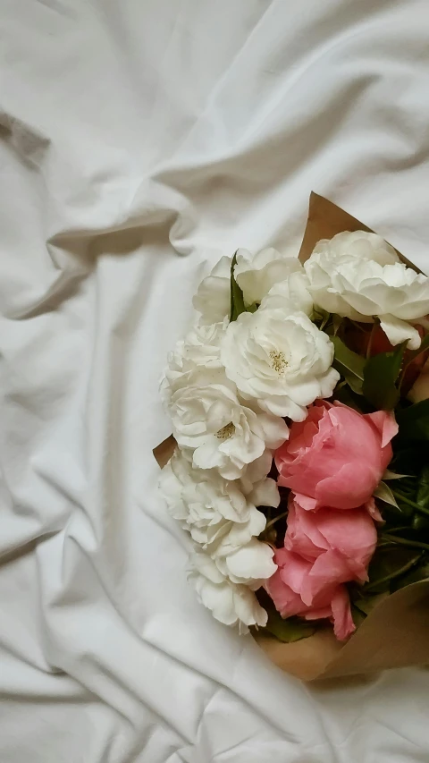 white and pink flowers are arranged on top of the sheet