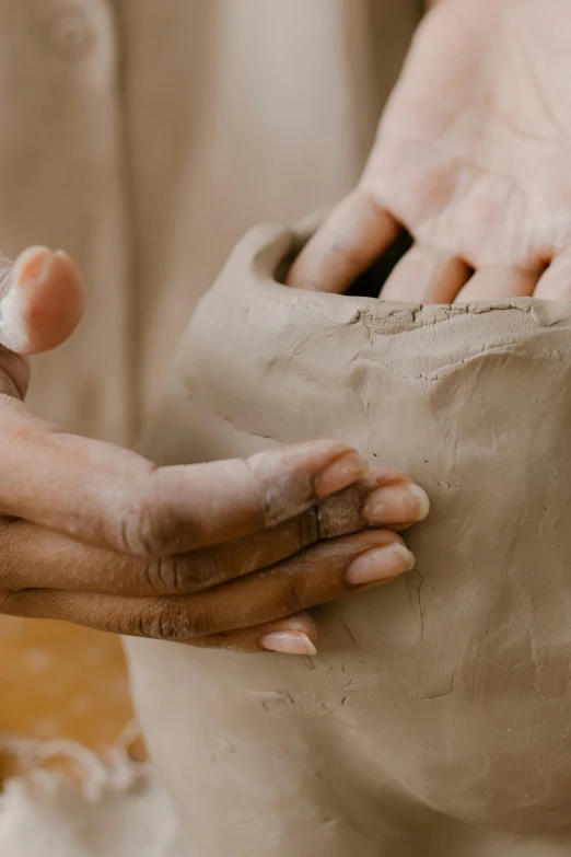 a person creating a vase out of clay with two hands