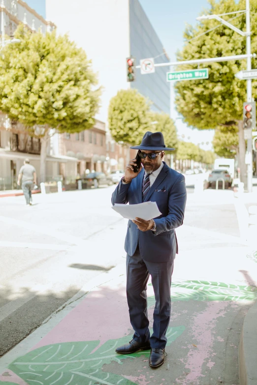 a man is standing on the sidewalk while talking on his cell phone