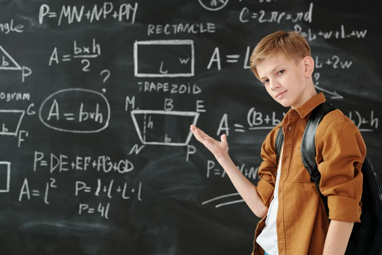 a boy stands in front of a blackboard with writing on it