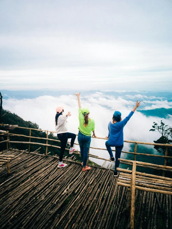 three people on top of a mountain looking out at the clouds