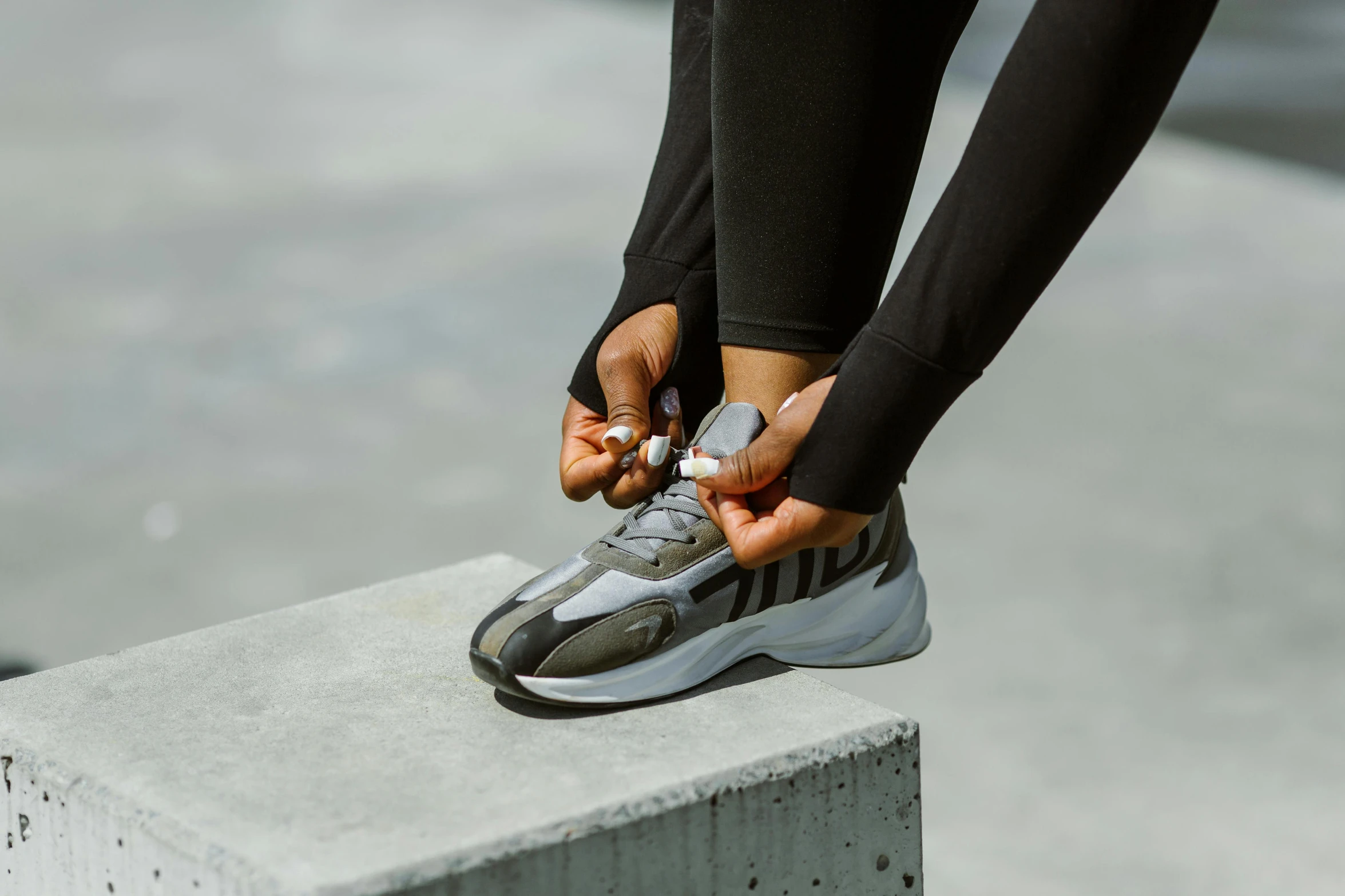 a woman is tying her shoelaces on the edge of a structure