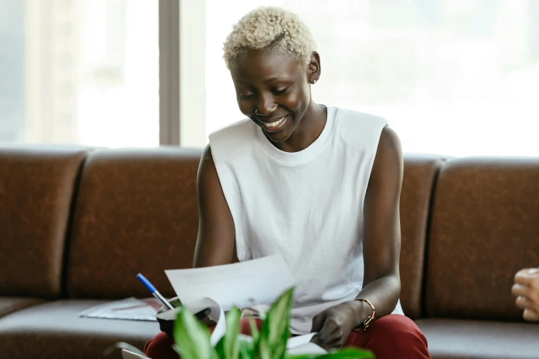 two people sitting on a couch reading paper