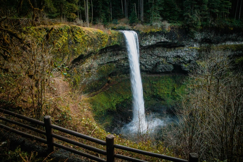 the view of the waterfall is seen from behind the fence