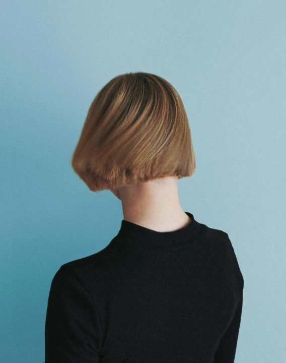 the back view of a woman's head against a blue wall