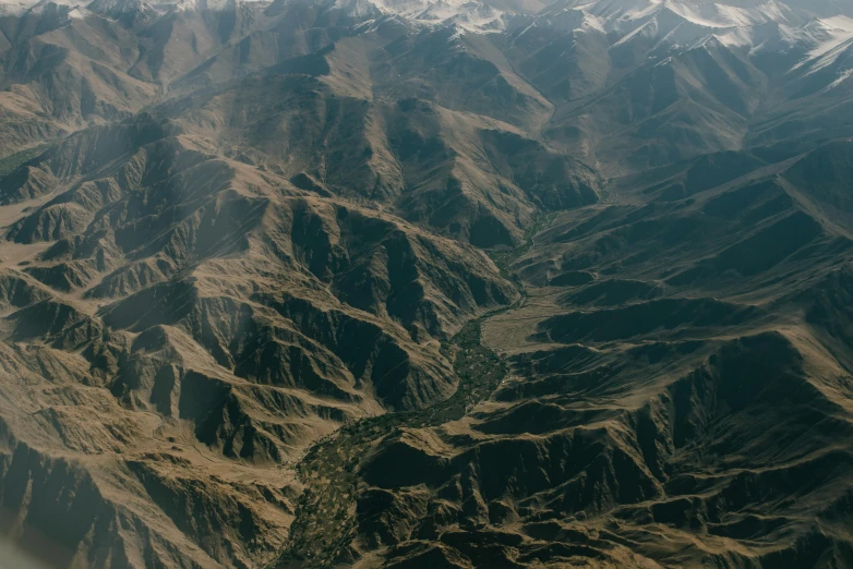 looking down on a valley covered in brown mountains